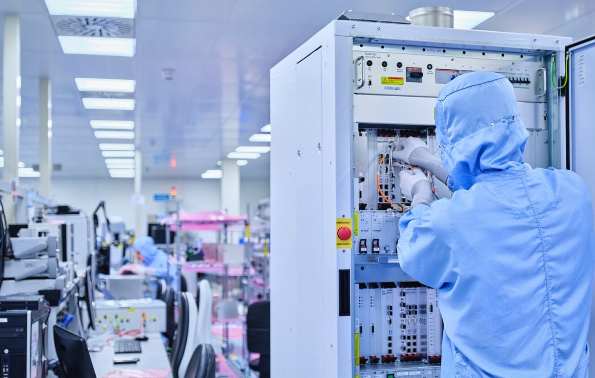 Mitarbeiter im Reinraumanzug arbeitet an einem Elektronikschrank bei Neways in Riesa