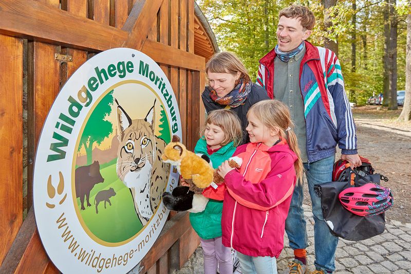 Familie mit zwei Kindern am Eingangsschild des Wildgeheges Moritzburg
