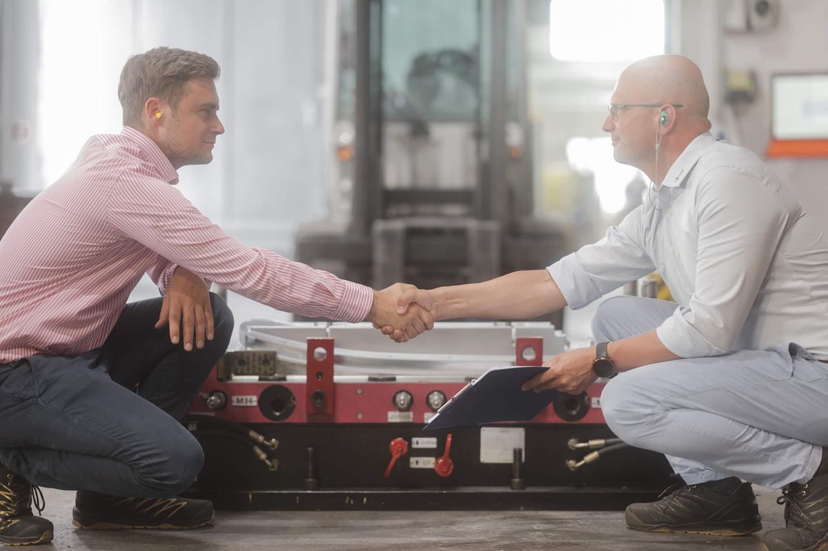 Zwei Männer geben sich vor einem neuen Werkzeug bei Mitras Composites Systems die Hand