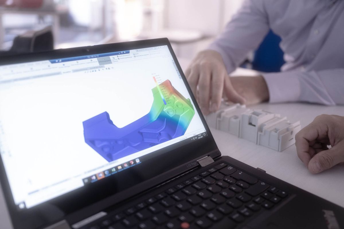 Notebook zeigt eine Festigkeitssimulation eines Bauteils, daneben Musterteile von Mitras Composites Systems