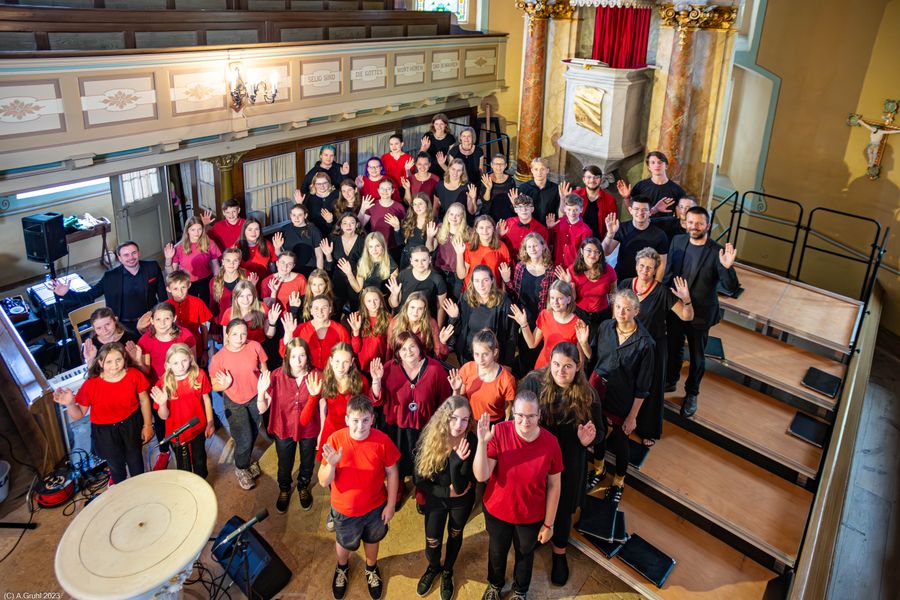Chor in roter und schwarzer Kleidung singt beim Diakoniesonntag in einer Kirche