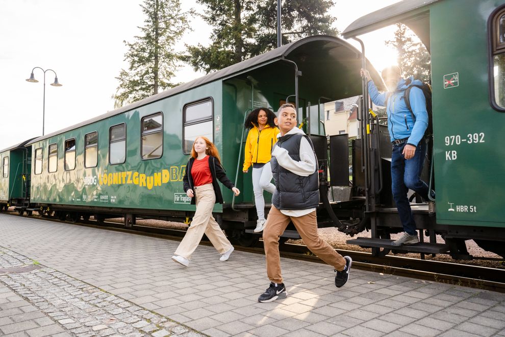 Jugendliche steigen am Haltepunkt aus einem Wagen der Lößnitzgrundbahn