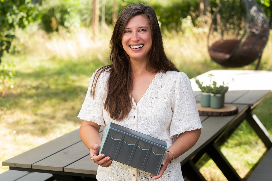 Junge Frau hält im Garten ein Bauteil aus Verbundwerkstoff in den Händen