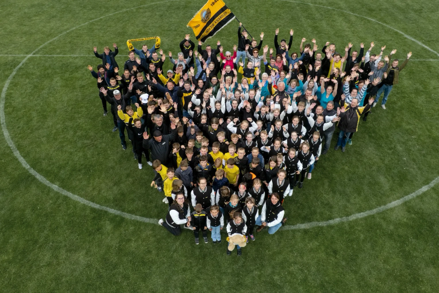 Mitglieder des SV Traktor Kalkreuth bilden auf dem Sportplatz zum 100-jährigen Jubiläum eine Herzform