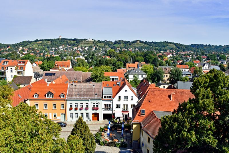 Blick von oben auf eine Altstadt mit kleinen Häusern und einer Straße aus Backsteinpflaster.