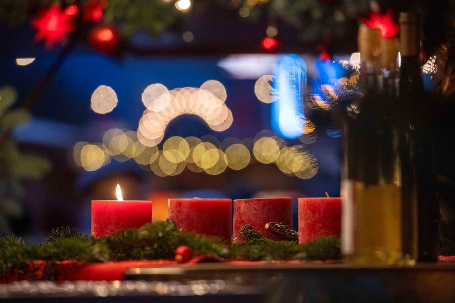 Adventskranz mit brennender Kerze auf dem Weihnachtsmarkt Altkötzschenbroda, dahinter Lichterketten