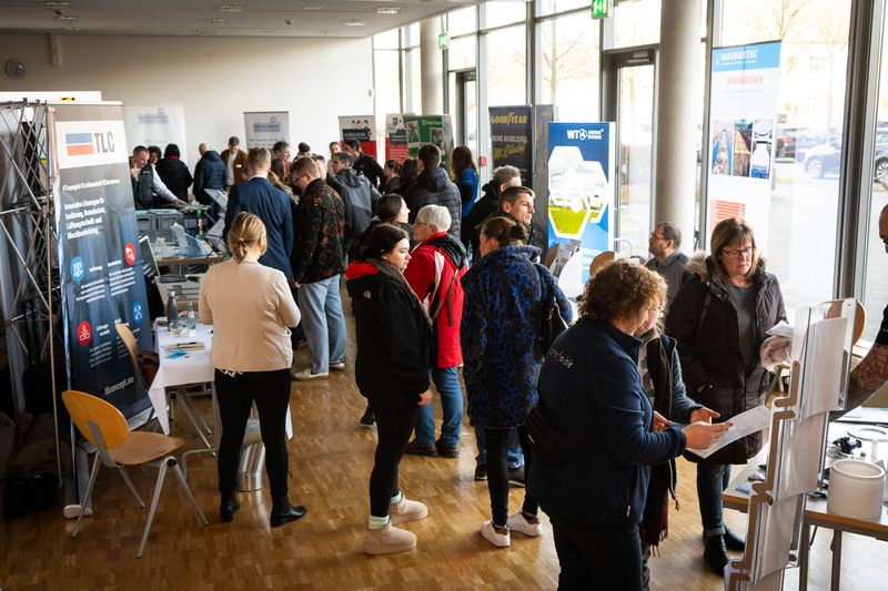 Besucherinnen und Besucher an Messeständen in einem Foyer