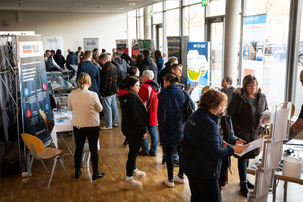 Besucherinnen und Besucher an Messeständen in einem Foyer